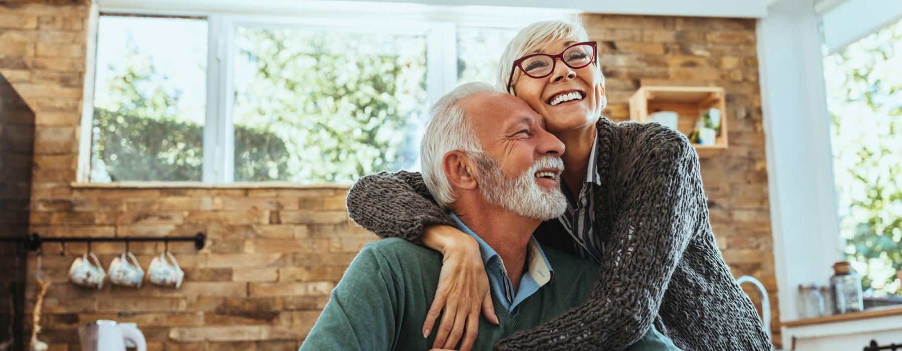 older couple hugging in their sun-filled kitchen